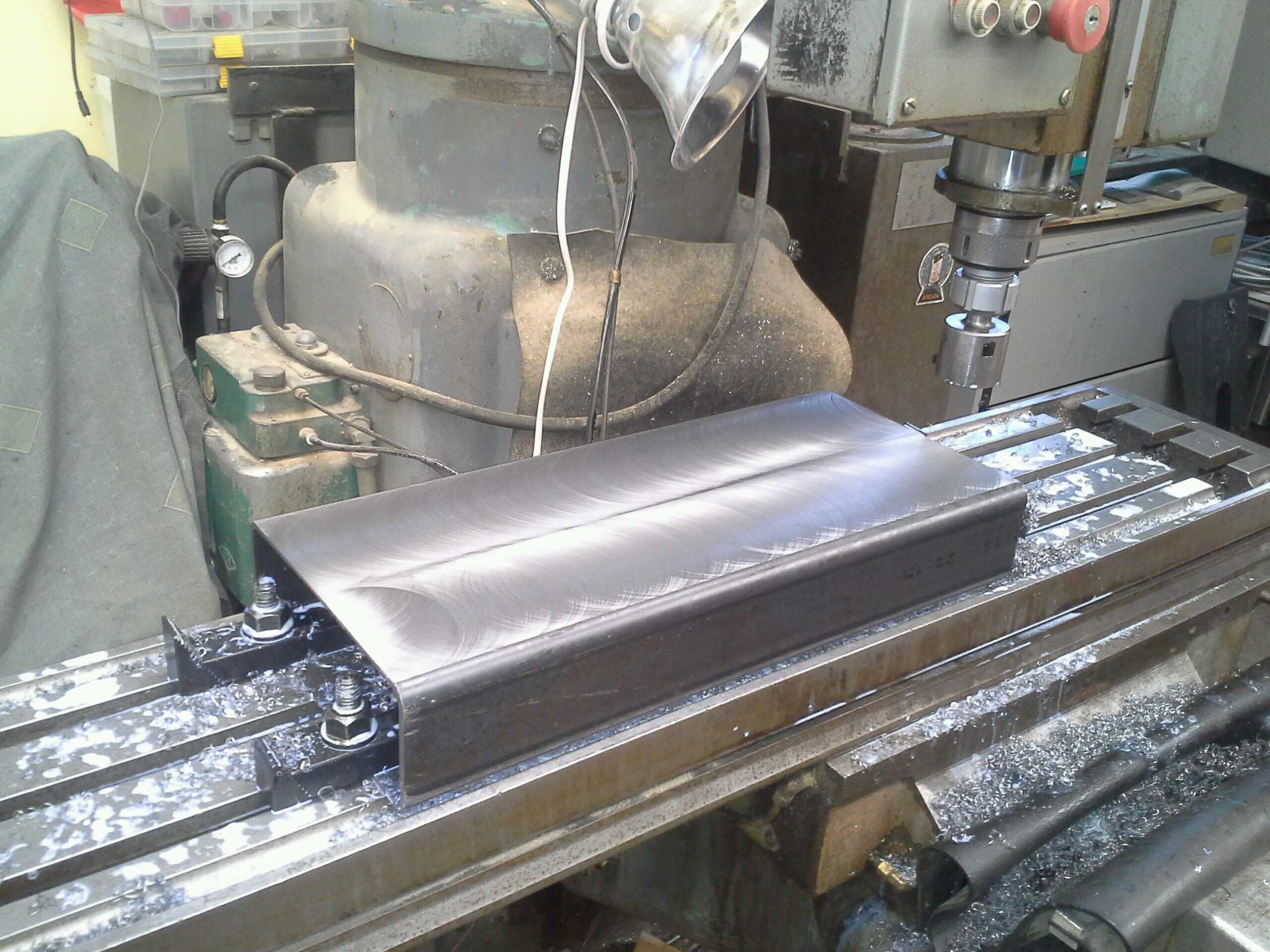 the steel for the frame fully faced, cutting fluid and chip still visible on table